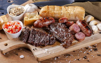 Grilled meats and sides on a wooden board at a Brazilian steakhouse in Rio de Janeiro.
