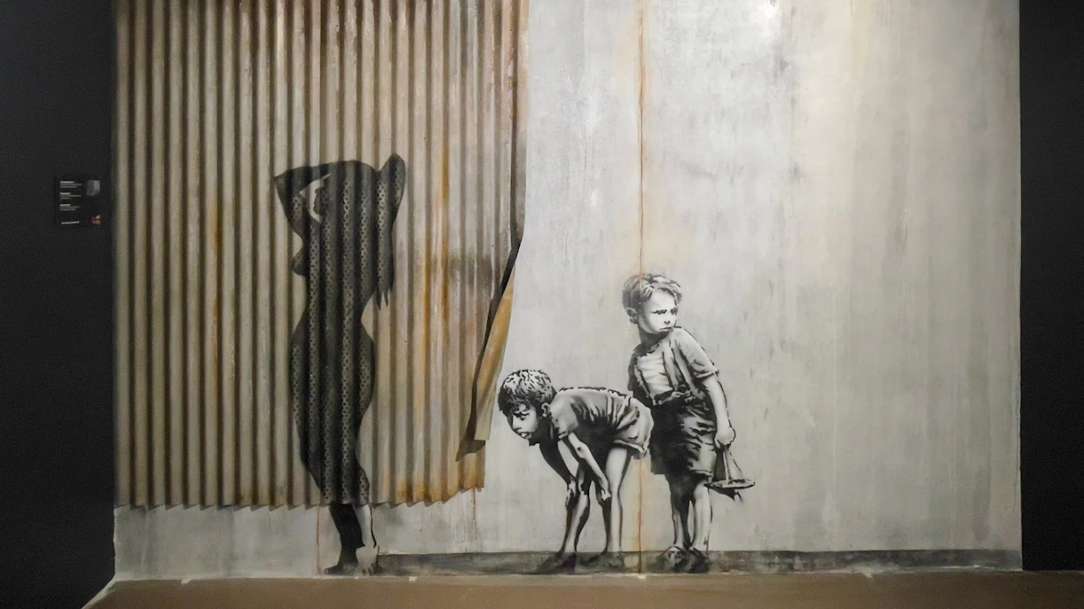 Children peering behind curtain artwork at Banksy Museum, Amsterdam.