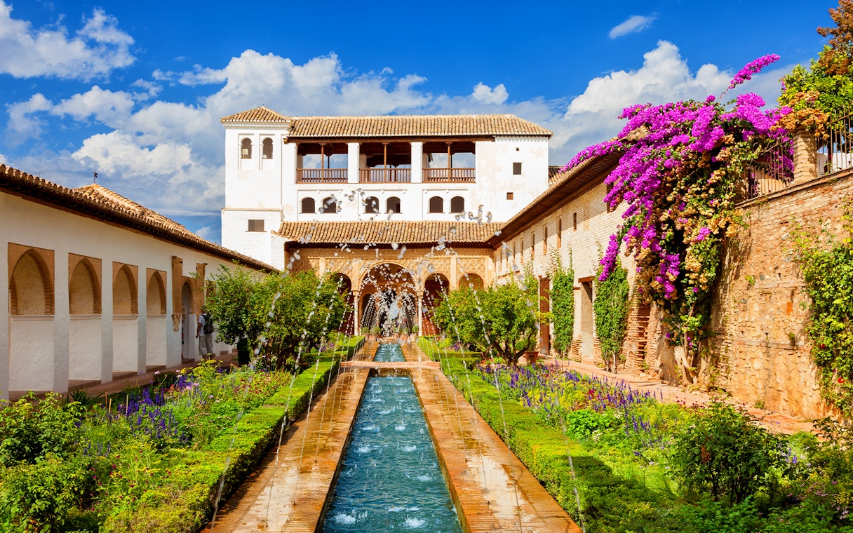 Gardens and fountains at Alhambra Palace, Granada, with vibrant flowers and historic architecture.