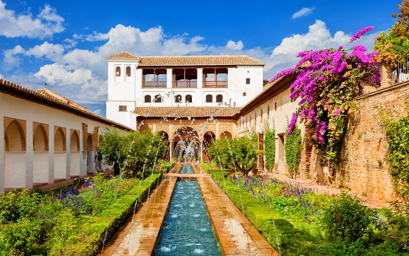 Gardens and fountains at Alhambra Palace, Granada, with vibrant flowers and historic architecture.