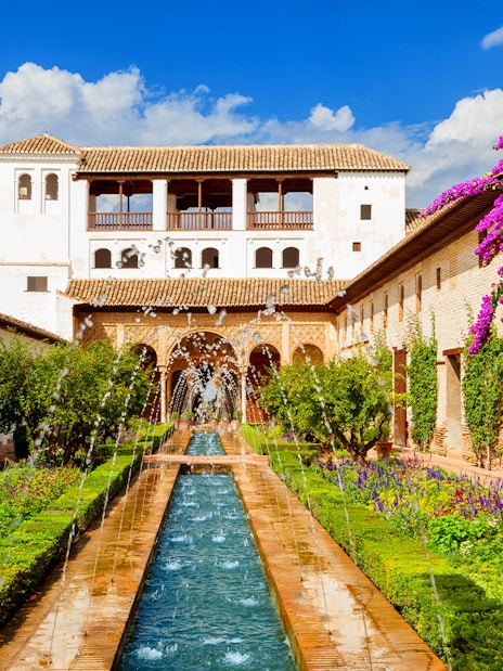 Gardens and fountains at Alhambra Palace, Granada, with vibrant flowers and historic architecture.