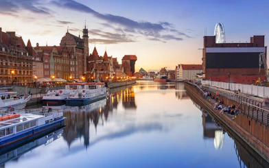 Sunset view of Gdansk River with boats and historic buildings, ideal for a cruise with Prosecco.