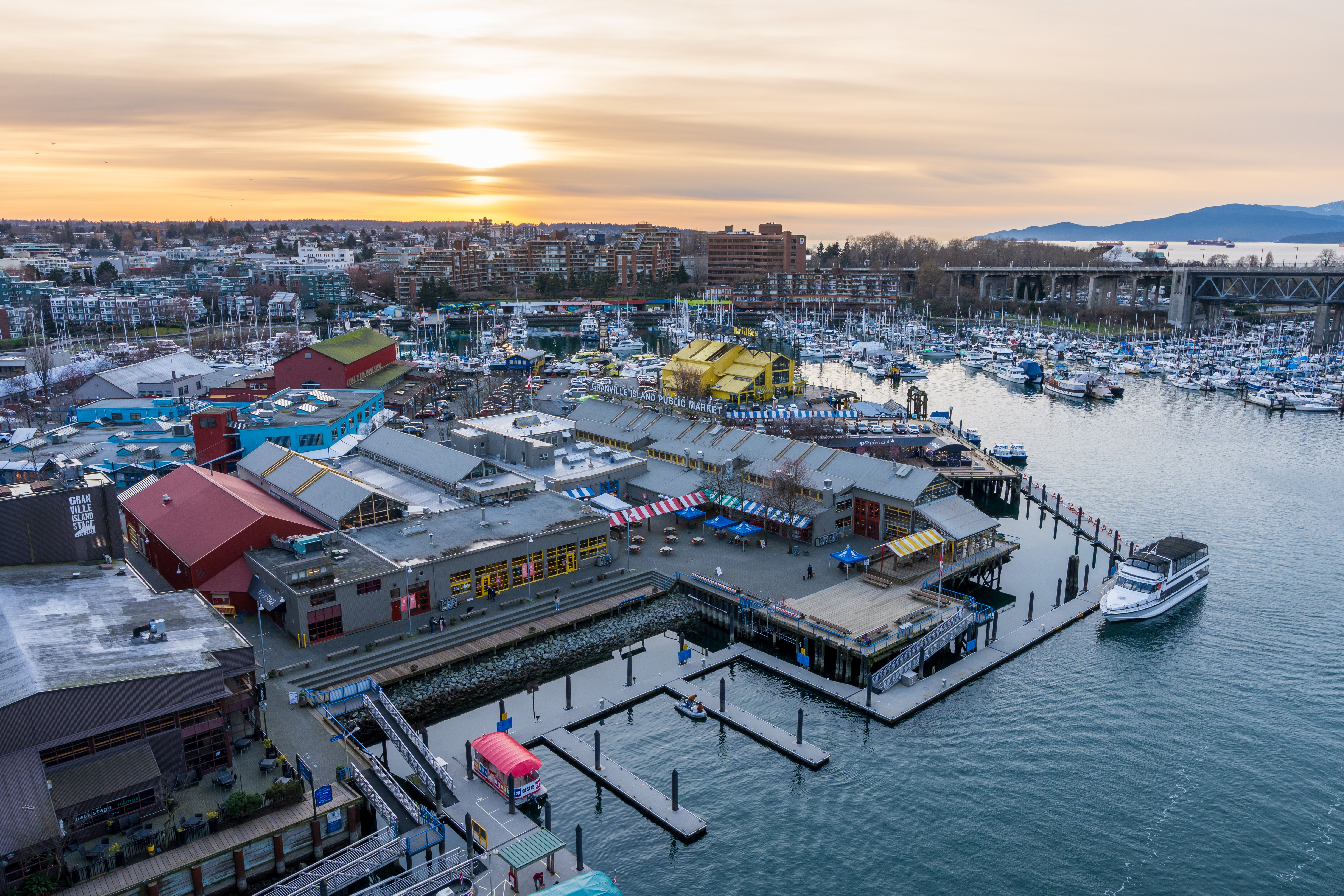 Granville Island Public Market and Marina at dusk with Vancouver skyline in the background, Canada.