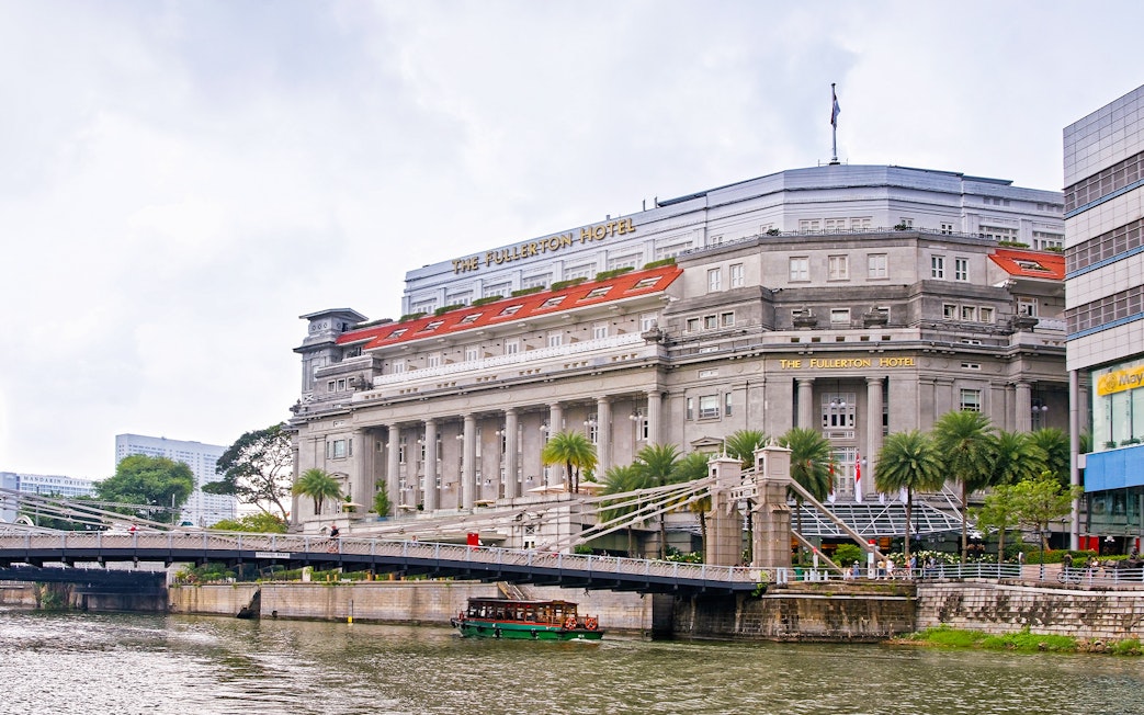 Fullerton Hotel in Singapore with a view of the river and nearby bridge.
