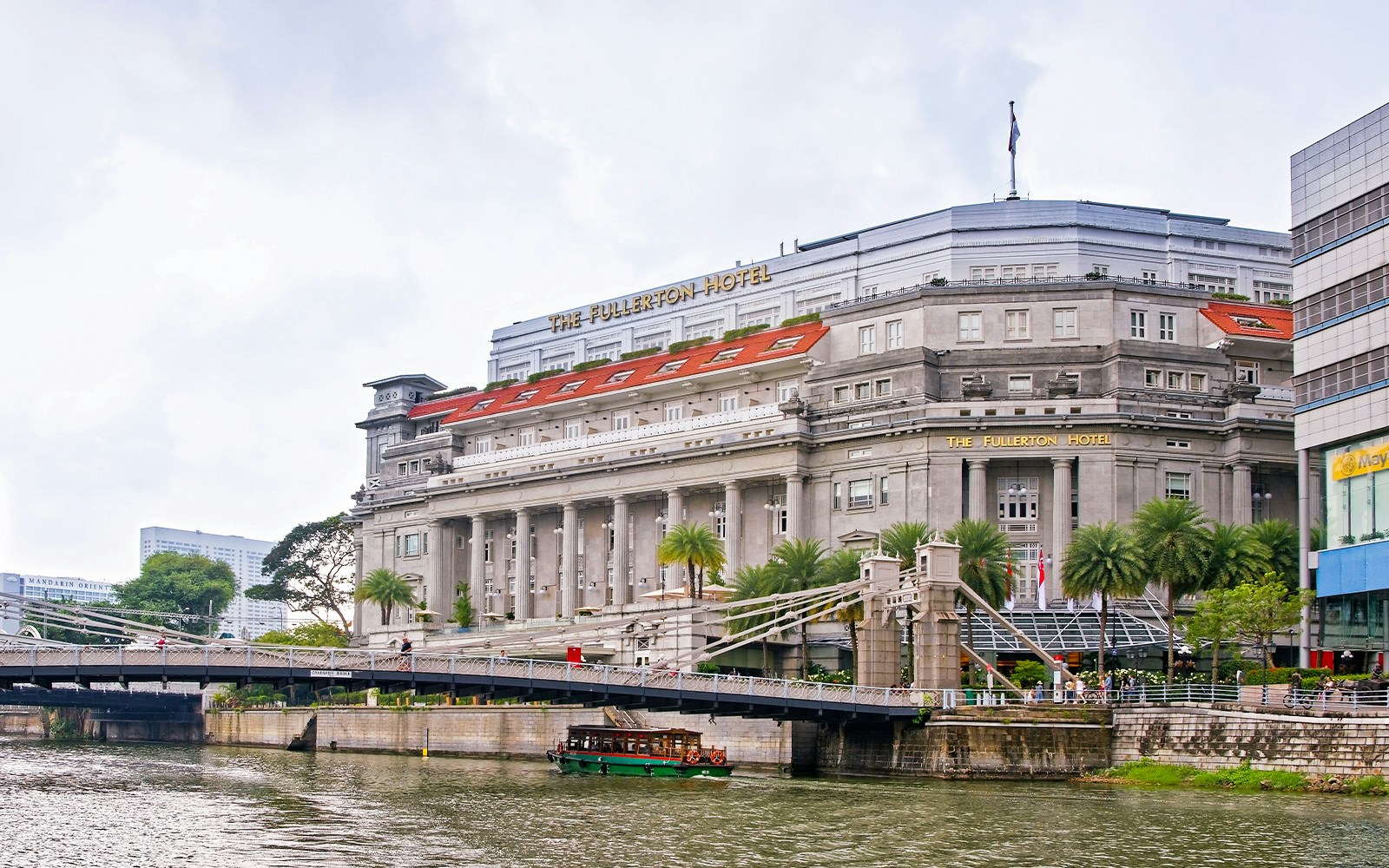 Fullerton Hotel in Singapore with a view of the river and nearby bridge.