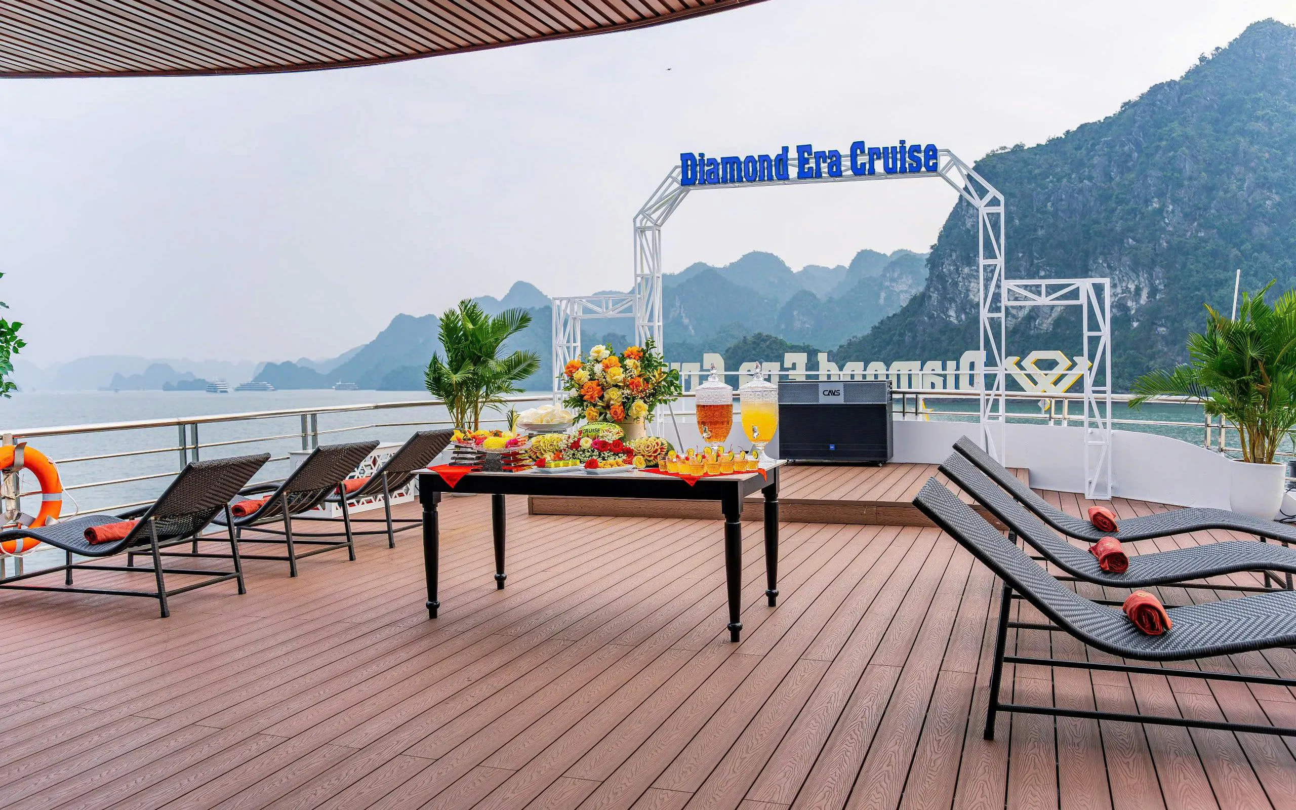 Luxury cruise deck with lounge chairs and refreshments, Ha Long Bay backdrop.