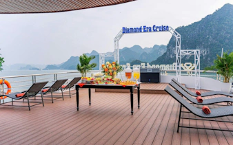 Luxury cruise deck with lounge chairs and refreshments, Ha Long Bay backdrop.