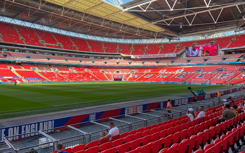 Wembley Stadium interior with red seats and green pitch, London.