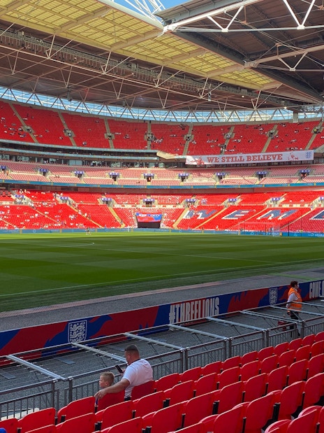 Wembley Stadium interior with red seats and green pitch, London.