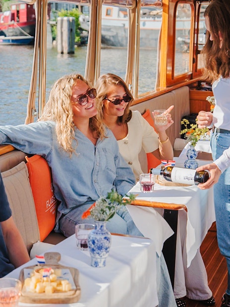 Guests enjoying cheese and wine on a canal cruise in Amsterdam.