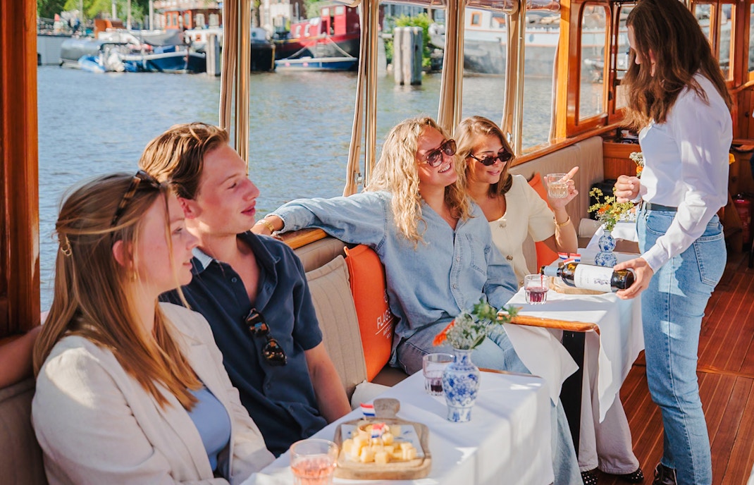 Guests enjoying cheese and wine on a canal cruise in Amsterdam.