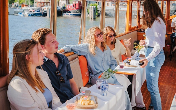 Guests enjoying cheese and wine on a canal cruise in Amsterdam.
