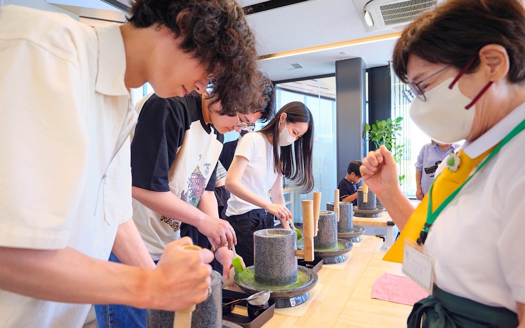 Adults participating in a matcha making class using traditional tools.