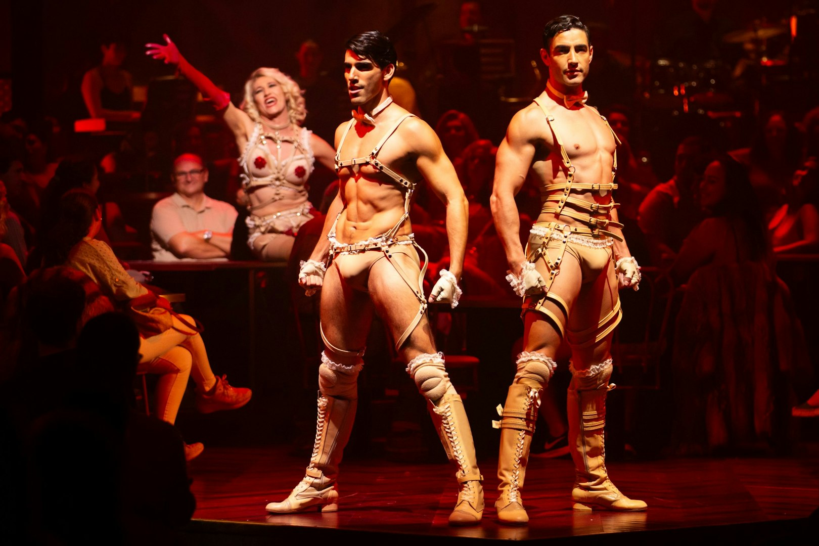 Cabaret performers on stage during a Madrid show, with audience in the background.