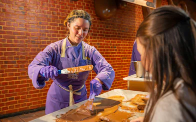 Chocolate-making demonstration at Cadbury World with a guide assisting a visitor.