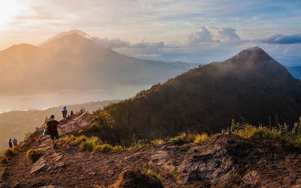 Hikers on Mount Batur trail with sunrise view in Bali, Indonesia.