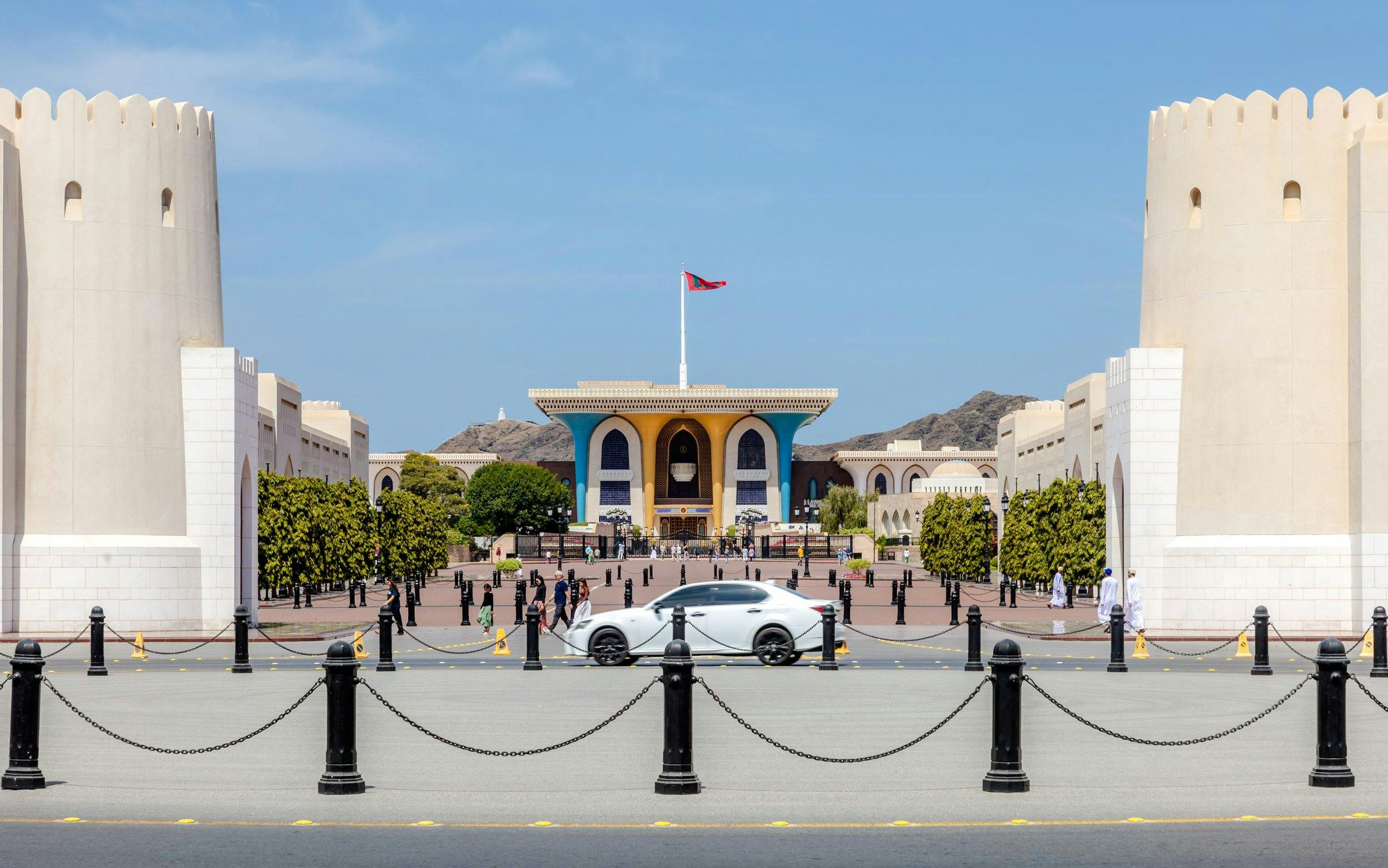 Al Alam Palace in Muscat with its distinctive blue and gold facade, surrounded by white towers.