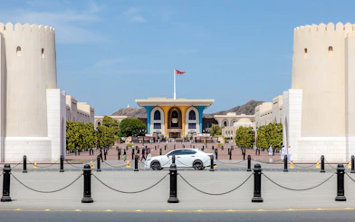 Al Alam Palace in Muscat with its distinctive blue and gold facade, surrounded by white towers.