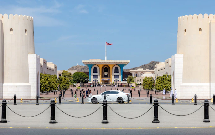 Al Alam Palace in Muscat with its distinctive blue and gold facade, surrounded by white towers.