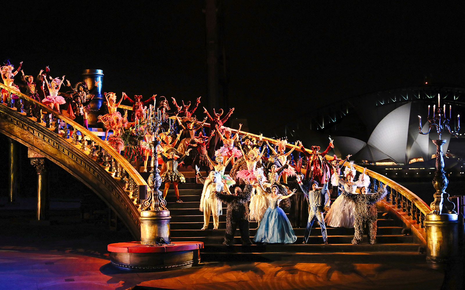 Performers in vibrant costumes on stage during The Phantom of the Opera on Sydney Harbour.