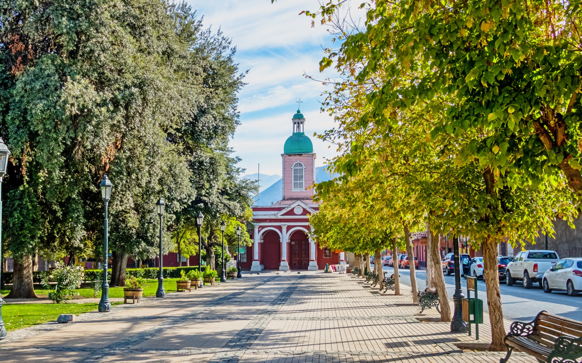 Church in Cajón del Maipo, Chile, with tree-lined path and benches.