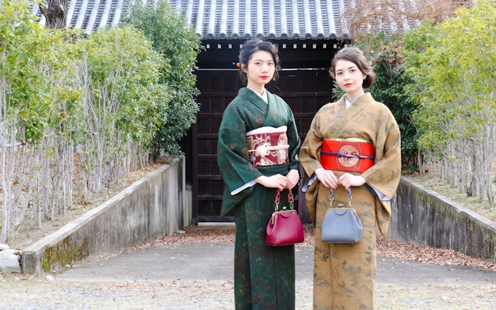 People in traditional Japanese kimonos standing in front of a wooden gate.