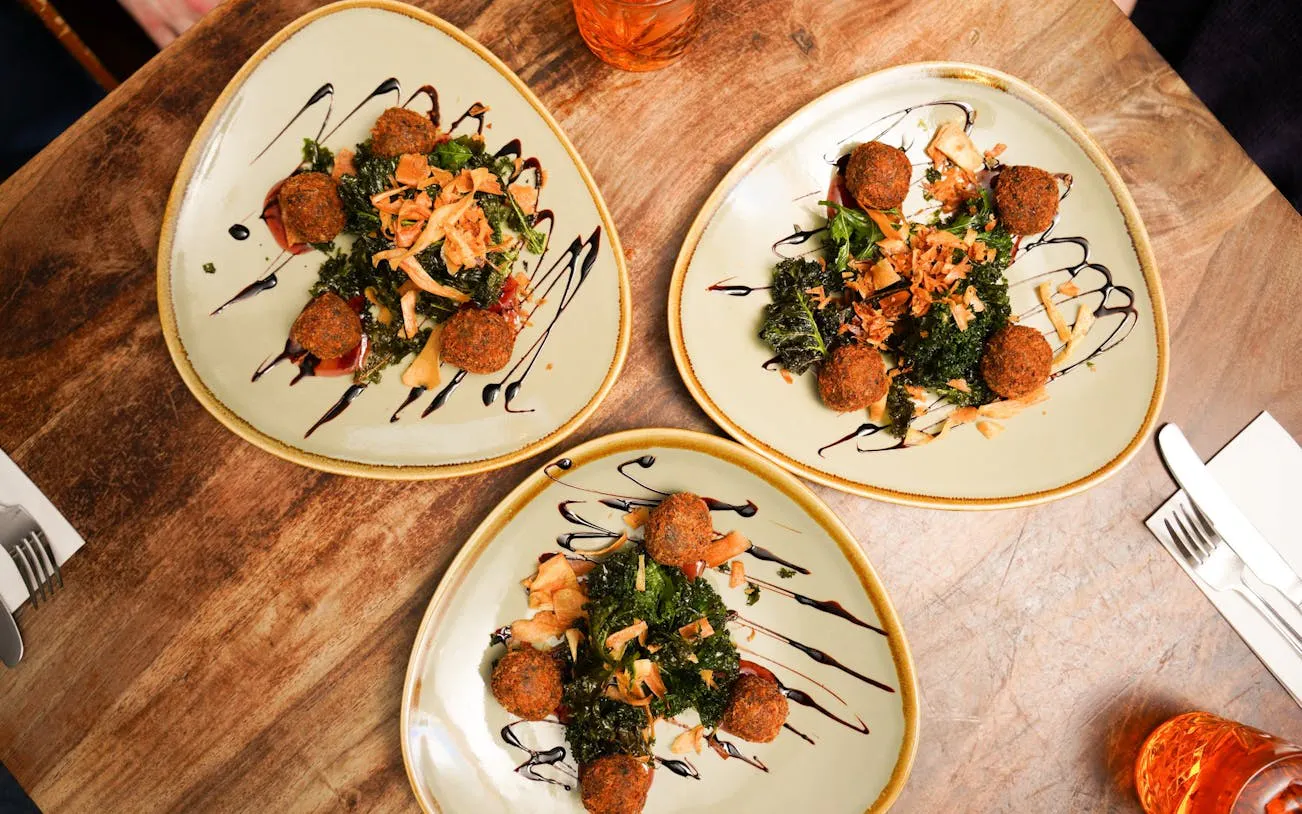 Plates of Scottish haggis balls with greens and sauce on Edinburgh food tour.