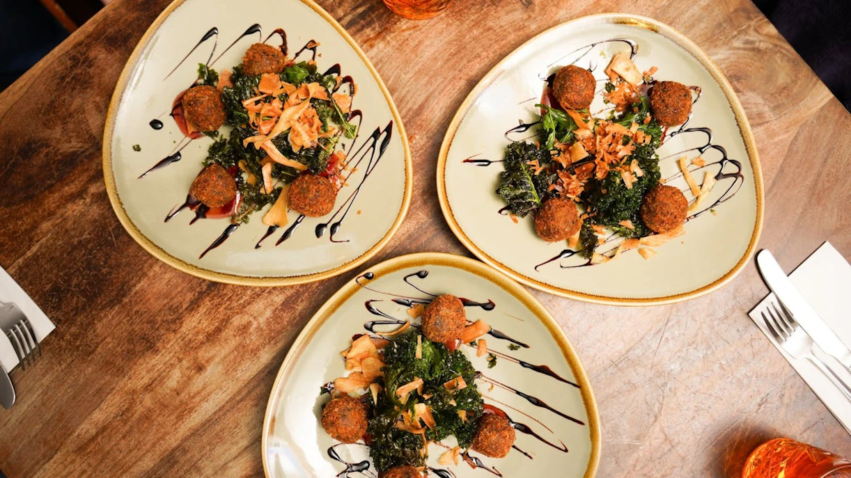 Plates of Scottish haggis balls with greens and sauce on Edinburgh food tour.