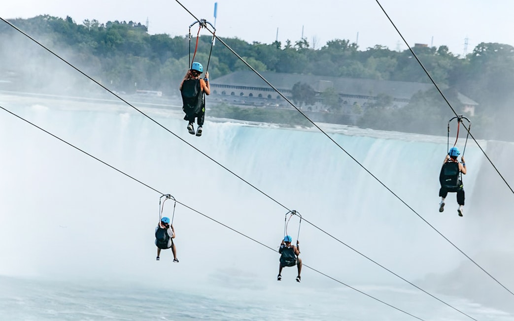 People ziplining towards Niagara Falls.