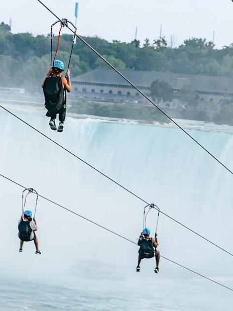 People ziplining towards Niagara Falls.