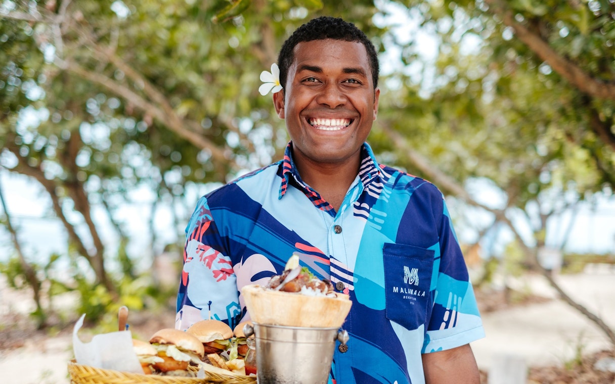 Man carrying meal at Malamala Beach Club, Fiji.