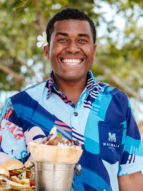 Man carrying meal at Malamala Beach Club, Fiji.