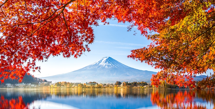 Reflection of Mt. Fuji in Lake Kawaguchi framed by autumn leaves.