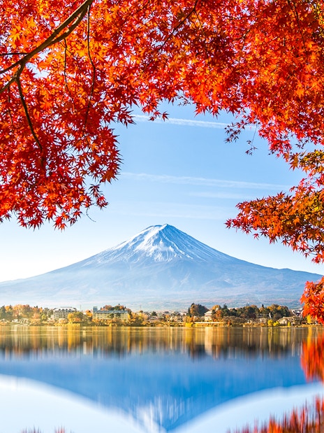 Reflection of Mt. Fuji in Lake Kawaguchi framed by autumn leaves.