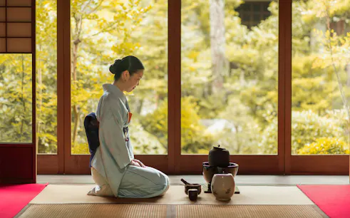 Woman in kimono performing tea ceremony in Kyoto teahouse.