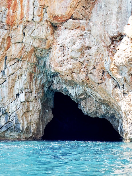 Blue cave entrance in Kotor Bay with rocky cliffs and turquoise water.