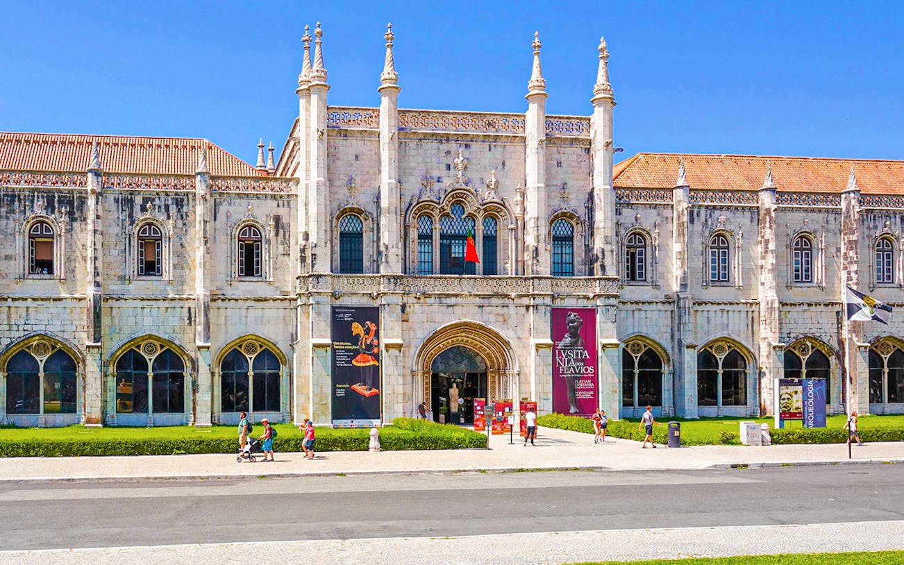 Exterior view of the Maritime Museum in Lisbon with visitors walking outside.