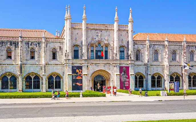 Exterior view of the Maritime Museum in Lisbon with visitors walking outside.