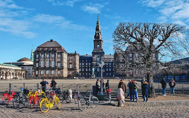 Christiansborg Palace in Copenhagen with tourists and colorful bicycles in the foreground.