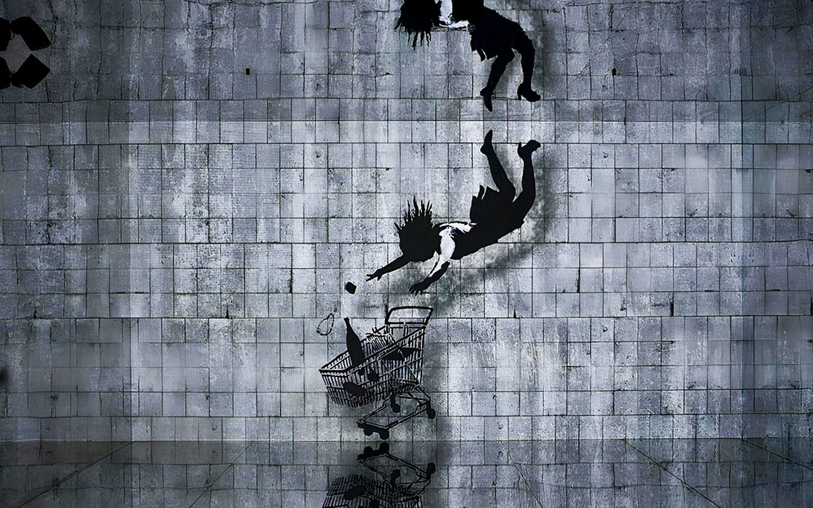 Street art mural by Banksy depicting a figure falling towards a shopping cart.