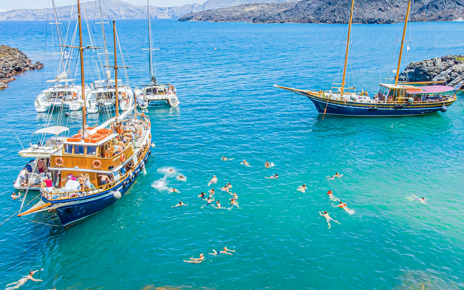 Santorini volcanic islands cruise with view of Palea Kameni hot springs and Thirassia in the background.