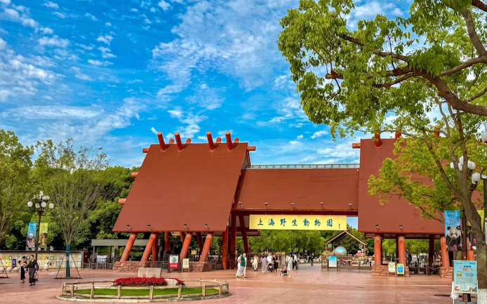 Entrance to Shanghai Wild Animal Park with visitors walking nearby.