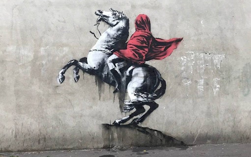 Street art of a hooded figure on a rearing horse, related to The Little Prince exhibition.
