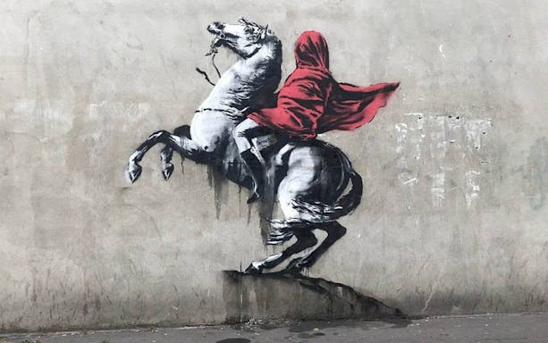 Street art of a hooded figure on a rearing horse, related to The Little Prince exhibition.