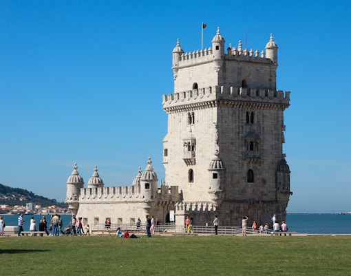 Belém Tower exterior with visitors in Lisbon, Portugal.
