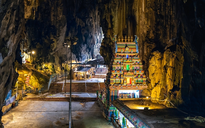 Hindu temple inside Batu Caves with colorful facade and rocky cave walls.