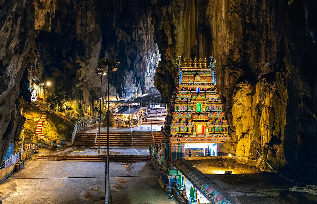 Hindu temple inside Batu Caves with colorful facade and rocky cave walls.