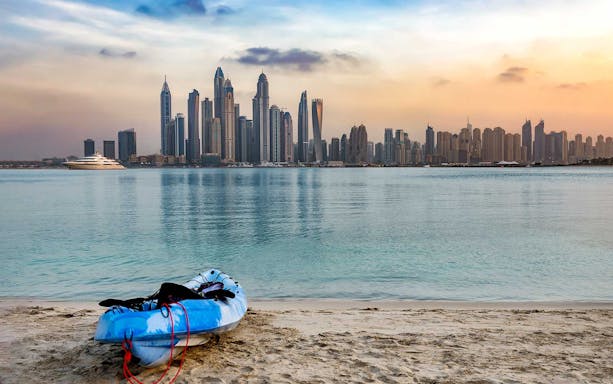 Kayak on Dubai beach with city skyline in the background.