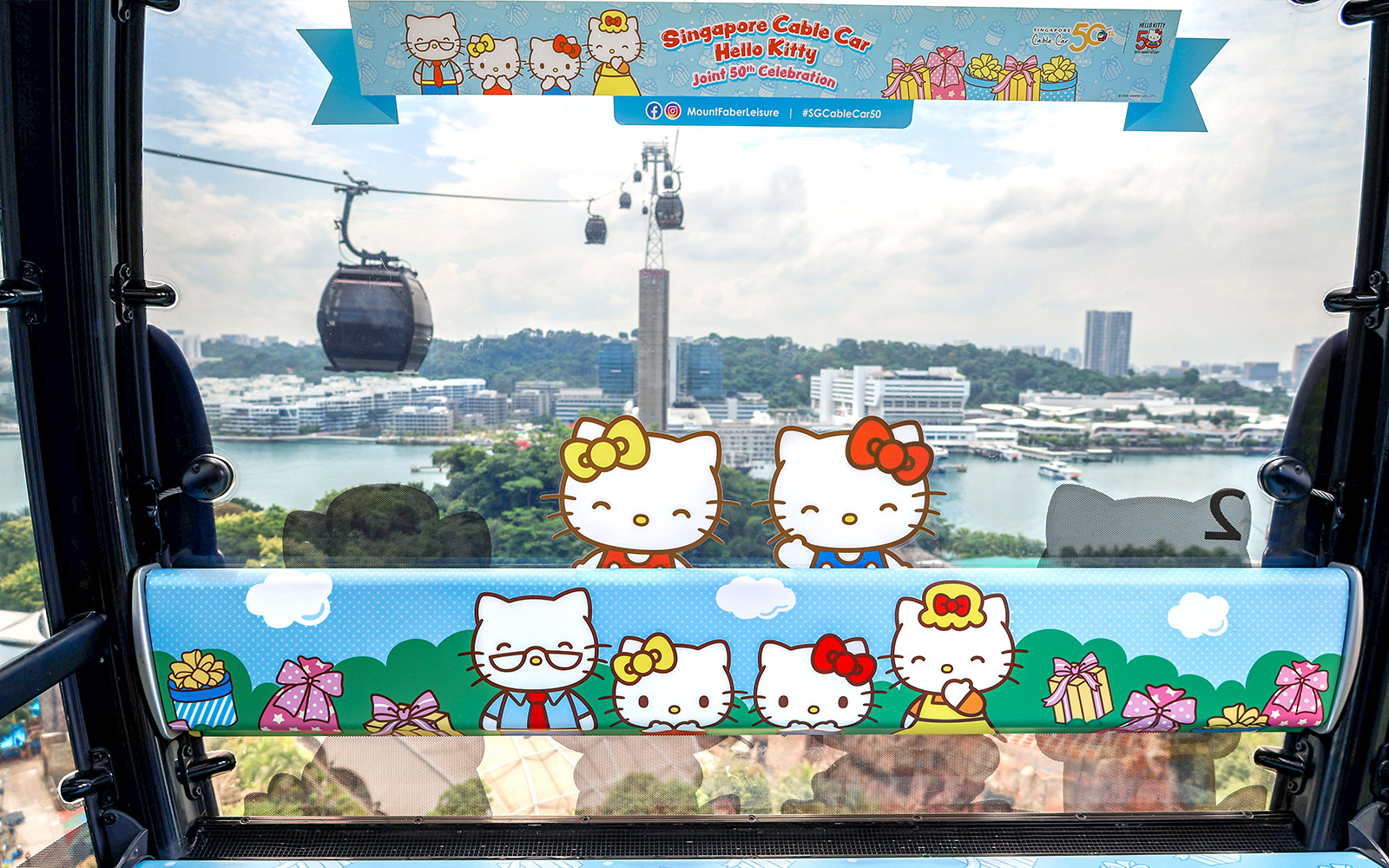 Singapore Cable Car decorated with Hello Kitty theme, overlooking cityscape and harbor.
