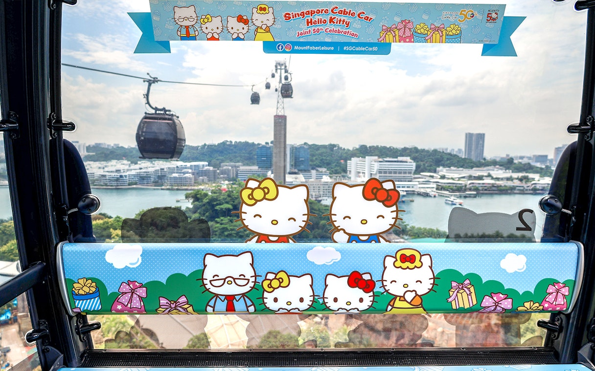 Singapore Cable Car decorated with Hello Kitty theme, overlooking cityscape and harbor.
